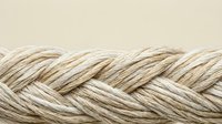 Natural hemp rope with detailed braided texture pattern on neutral beige background for crafting and nautical projects.