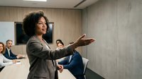Professional African American businesswoman presenting to colleagues in modern conference room during corporate meeting or training session.