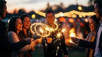 Group of diverse young adults holding lit sparklers at outdoor evening celebration with string lights and bokeh background, suitable for festive events, parties, and social gatherings.