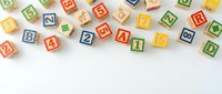 Colorful wooden alphabet blocks scattered on white background with letters and numbers for educational play and learning activities.