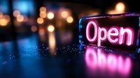 Neon open sign glowing with pink and blue lights against blurred city bokeh background at night for business storefront and retail shop advertising.