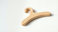 Wooden clothes hanger lying flat on white background, isolated minimalist wardrobe accessory with smooth natural finish and rounded edges.