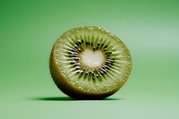 Fresh juicy kiwi fruit half showing detailed seed pattern and vibrant green flesh on green background with soft shadow, macro food photography.