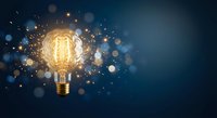 Glowing vintage Edison bulb with sparks and bokeh lights on dark blue background symbolizing creativity, innovation and bright ideas for business concepts.