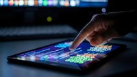 Businessman analyzing financial data on digital tablet with colorful charts and graphs in modern office environment for investment decisions.