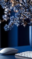 Dried blue flowers in modern workspace with computer mouse and keyboard creating elegant office decor and natural botanical arrangement.