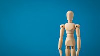 Wooden artist mannequin figure standing on blue background for creative design projects and artistic presentations.