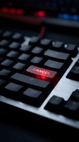 Red illuminated cancel key on black laptop keyboard with blurred colorful lights in background creating dramatic tech atmosphere for business concepts.