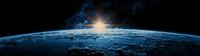 Panoramic view of planet Earth from space with bright sunrise over curved horizon, glowing atmosphere and stars in dark cosmos background.