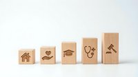 Wooden blocks with engraved icons showing life priorities progression from home to health care and justice on white background.