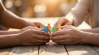 Family protection concept with hands sheltering paper cutout figures representing care, support, insurance and community unity in warm light.