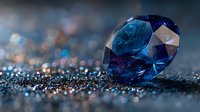 Stunning blue sapphire gemstone with brilliant cut facets on sparkling dark surface with bokeh lights creating luxury jewelry background for premium designs.