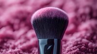Luxurious makeup brush with soft black bristles on pink textured background, professional cosmetic tool in dramatic lighting for beauty and fashion photography.