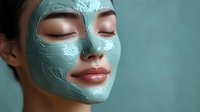 Woman with closed eyes wearing green clay facial mask for skincare treatment and spa relaxation.