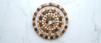 Circular wooden mosaic pattern with natural wood tones arranged in concentric rings on white marble surface for interior design and craft projects.