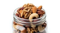 Mixed nuts assortment in glass jar with almonds, walnuts, cashews and pecans isolated on white background for healthy snacking and cooking recipes.