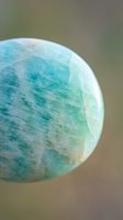 Polished green amazonite gemstone with natural marbled patterns and translucent surface displaying healing crystal properties for meditation and wellness practices.