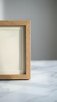 Empty wooden picture frame with beige mat on marble surface against gray wall background for home decor and interior design projects.