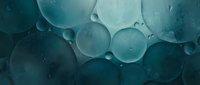 Close-up of translucent spheres floating in teal liquid with water droplets, creating an abstract molecular or scientific background for design and editorial use.