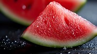 Fresh juicy watermelon slice with water drops on dark background, macro shot showing detailed texture of ripe red fruit flesh and green rind. Food photography.
