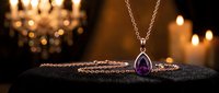Elegant silver necklace with amethyst teardrop pendant displayed on black velvet against candlelit backdrop. Luxury jewelry photography for retail and fashion marketing.