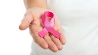 Hand holding pink ribbon symbol for breast cancer awareness campaign and women health support on white background.