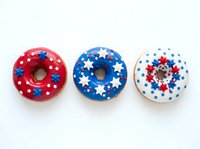 Patriotic glazed donuts decorated with star sprinkles in red, white and blue colors, isolated on white background, suitable for holiday baking, bakery designs and festive food photography.
