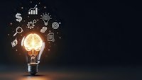 Glowing light bulb with business icons floating around representing innovation, creativity, strategy and growth concepts on dark background.