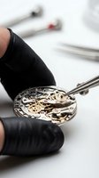 Watchmaker in black gloves assembling luxury mechanical watch movement with tweezers, gold gears visible, precision craftsmanship on white background.