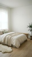 Minimalist bedroom with natural light from sheer curtains, neutral striped bedding, wooden bed frame, potted plant, and soft rug for serene home decor.