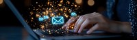 Digital communication concept with glowing email icons floating above laptop keyboard while person types, surrounded by magical light particles and bokeh effects.