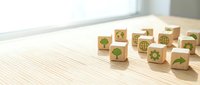 Wooden cubes with green eco icons on a light table, representing sustainability, environment, and global responsibility concepts.