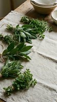 Fresh culinary herbs including sage, thyme and rosemary arranged on rustic wooden cutting board with mortar and pestle for cooking and seasoning.