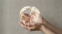 Hand holding glowing transparent globe with world map, representing global business, international connectivity, and worldwide communication networks for corporate concepts.