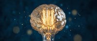 Vintage Edison bulb with glowing filament against dark blue bokeh background creates warm atmospheric lighting for interior design and decoration concepts.
