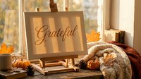 Cozy autumn home decor with grateful sign on easel, pumpkins, warm blanket and coffee mug creating seasonal thanksgiving atmosphere by sunny window.