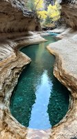 Turquoise river flowing through dramatic limestone canyon with towering rock walls and autumn foliage, ideal for travel and nature design projects.