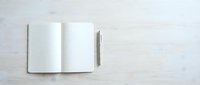 Open notebook with blank dotted pages and pen on white wooden surface, ready for writing, planning, journaling, or business notes.