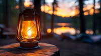 Glowing vintage oil lamp on wooden surface against blurred sunset forest background, creating warm atmospheric lighting and nostalgic outdoor ambiance.