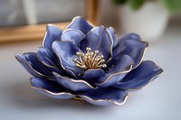 Elegant navy blue ceramic flower with golden stamens and delicate petal edges, decorative porcelain bloom on light surface for home decor and artistic display.