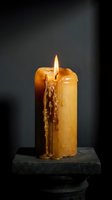 Burning yellow candle with melted wax dripping down sides on dark stone base against black background creating atmospheric mood lighting.