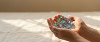 Close-up of hands holding colorful recycled plastic pellets or nurdles in sunlight, symbolizing sustainability, circular economy, and environmental responsibility for eco-friendly manufacturing.