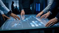 Business professionals analyzing digital data on interactive touchscreen table in modern office environment for strategic planning and decision making.