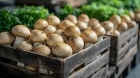 Fresh organic potatoes displayed in rustic wooden crates at farmers market with leafy green vegetables in background for healthy cooking and nutrition.