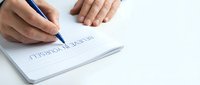 Professional man writing rejection notice on white paper with blue pen at office desk for business correspondence and formal communication.