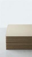 Stack of beige cardboard sheets on white surface for crafting and packaging projects in minimalist studio setting.