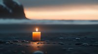 Glowing candle on dark beach with pebbles at sunset, creating peaceful atmosphere. Soft candlelight reflects on stones against blurred coastal background.