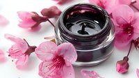 Luxurious black cosmetic cream jar with pink cherry blossom flowers on white background, elegant skincare product photography for beauty and spa marketing.