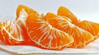 Fresh peeled tangerine segments showing juicy orange flesh and white pith on light background, ready for healthy snacking.