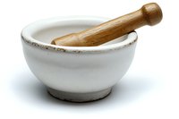White ceramic mortar and wooden pestle on isolated background, traditional grinding tool for herbs, spices and medicinal ingredients in kitchen and pharmacy.
